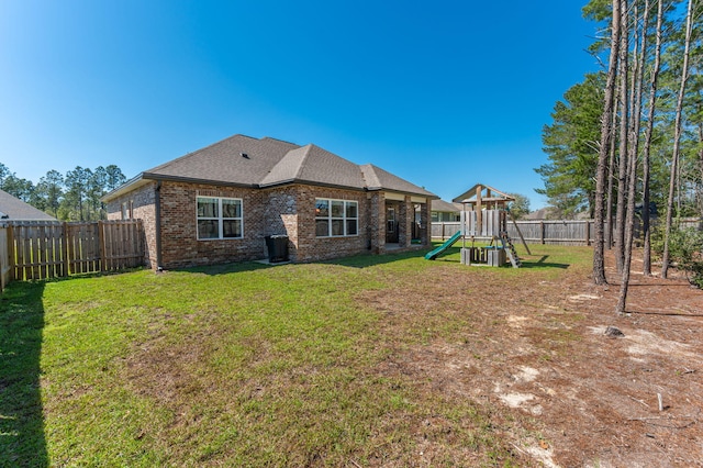 back of house featuring a playground, a lawn, brick siding, and a fenced backyard
