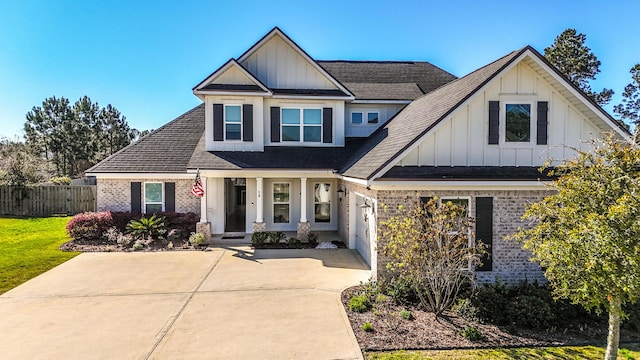 view of front of house featuring fence, board and batten siding, concrete driveway, a garage, and brick siding