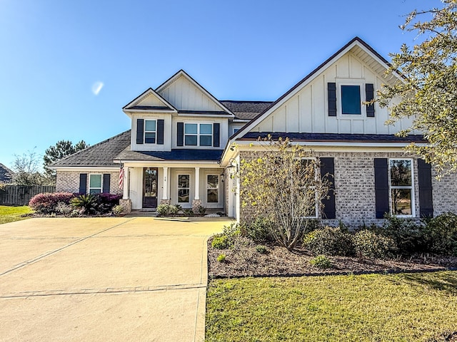 view of front facade featuring brick siding, board and batten siding, a front lawn, and fence