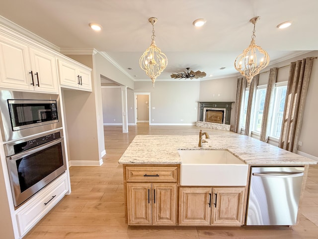 kitchen with a sink, stainless steel appliances, a fireplace with raised hearth, and a chandelier