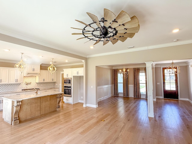 kitchen with an inviting chandelier, light wood-style flooring, tasteful backsplash, and stainless steel appliances