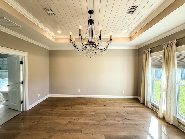 spare room with a tray ceiling, visible vents, and a chandelier