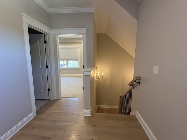 hallway with an upstairs landing, ornamental molding, baseboards, and wood finished floors