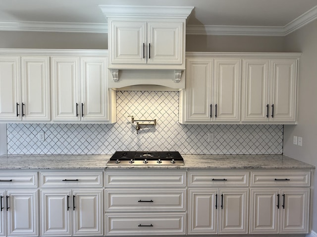 kitchen featuring premium range hood, tasteful backsplash, stainless steel gas stovetop, white cabinets, and crown molding