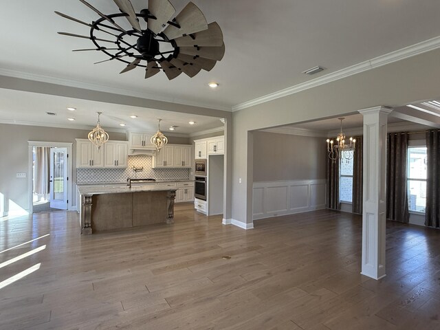 kitchen with a kitchen bar, an inviting chandelier, wood finished floors, and appliances with stainless steel finishes