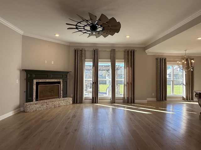 unfurnished living room with a notable chandelier, wood finished floors, baseboards, and ornamental molding