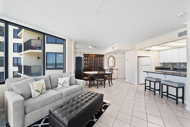 9850 S Thomas Dr Unit 205W, Panama City Beach, FL 32408 - living room with light tile patterned floors, baseboards, visible vents, ornamental molding, and a textured ceiling