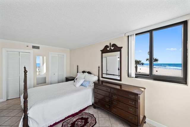 9850 S Thomas Dr Unit 205W, Panama City Beach, FL 32408 - bedroom featuring light tile patterned flooring, visible vents, a textured ceiling, and multiple closets