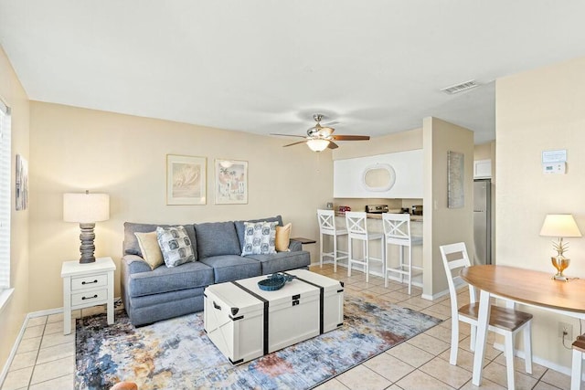 living area featuring light tile patterned floors, visible vents, baseboards, and a ceiling fan