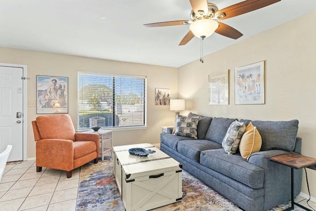 living area with light tile patterned floors, a ceiling fan, and baseboards
