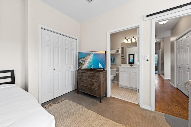 bedroom featuring carpet flooring, a sink, baseboards, a closet, and ensuite bath