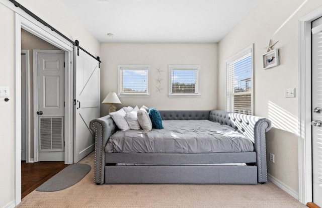 bedroom featuring carpet, visible vents, a barn door, and baseboards