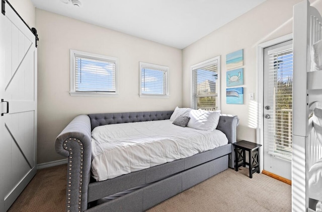 carpeted bedroom with a barn door, access to exterior, and baseboards