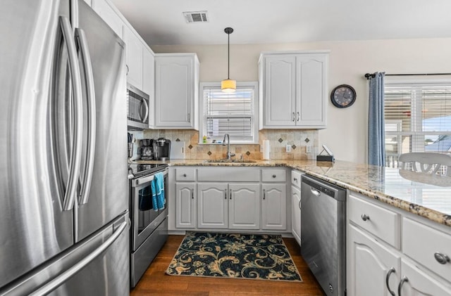 kitchen with dark wood finished floors, stainless steel appliances, white cabinets, a sink, and visible vents