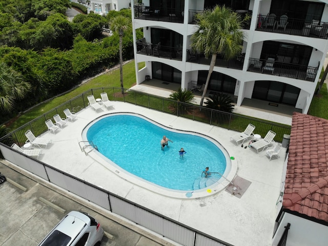 community pool featuring fence, a patio, and a lawn