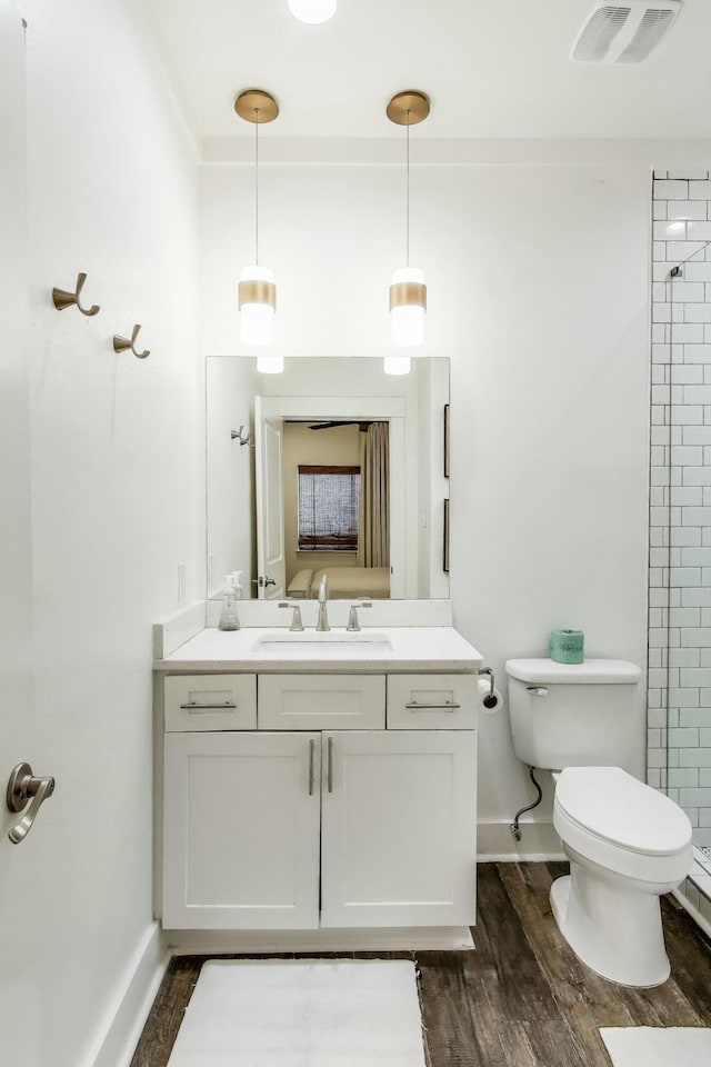 full bath featuring toilet, vanity, wood finished floors, and visible vents