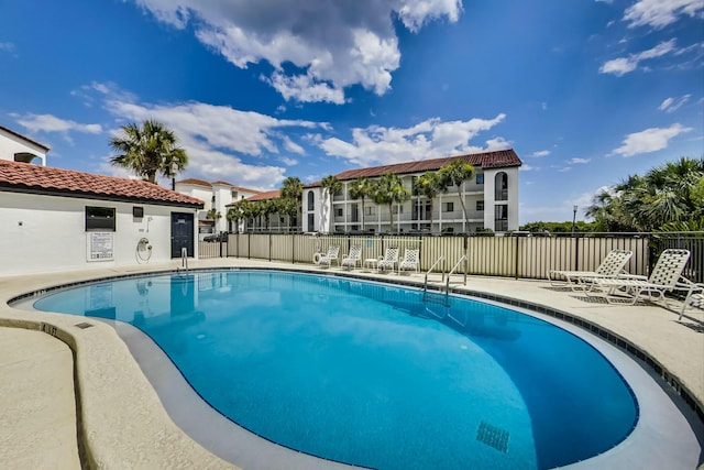community pool with a patio area and fence