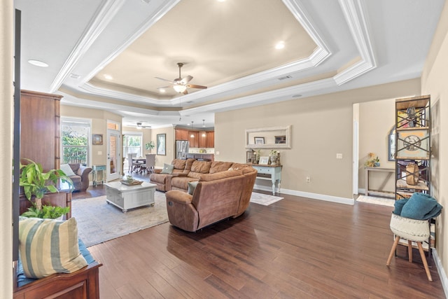living room with a raised ceiling, ceiling fan, ornamental molding, and wood-type flooring