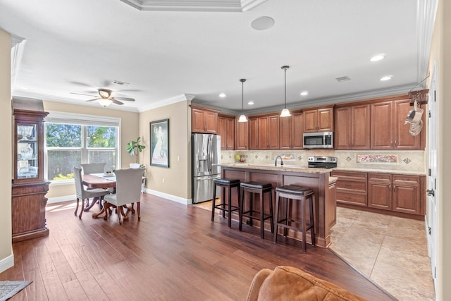 kitchen featuring brown cabinets, stainless steel appliances, crown molding, and baseboards