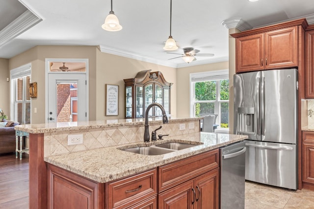 kitchen featuring a kitchen island with sink, a sink, ceiling fan, ornamental molding, and appliances with stainless steel finishes