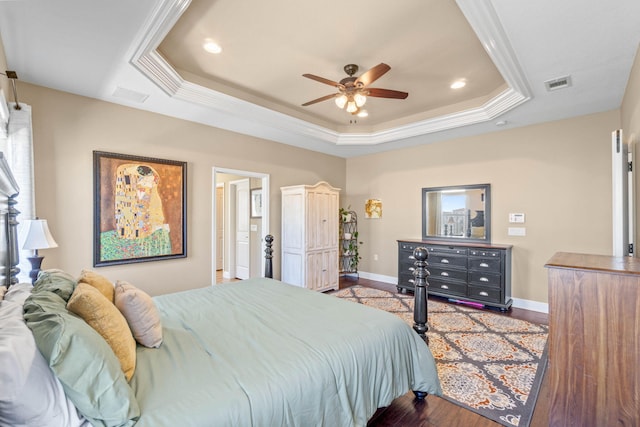 bedroom featuring visible vents, wood finished floors, a raised ceiling, and baseboards