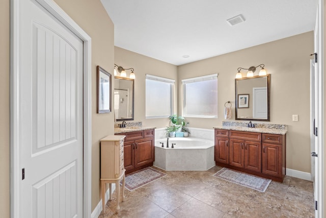 full bathroom featuring visible vents, two vanities, a garden tub, and a sink