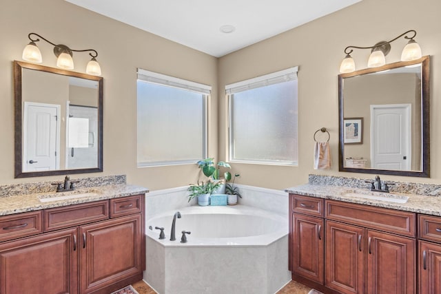 bathroom with two vanities, a garden tub, and a sink