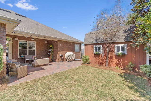 back of house featuring a patio, an outdoor hangout area, a shingled roof, a lawn, and brick siding