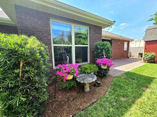exterior space with fence, a lawn, a patio, and brick siding