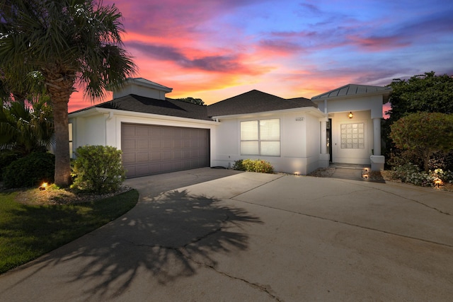 view of front facade with an attached garage, concrete driveway, and stucco siding