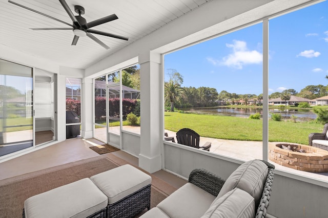 sunroom featuring a water view, an outdoor living space with a fire pit, and a ceiling fan