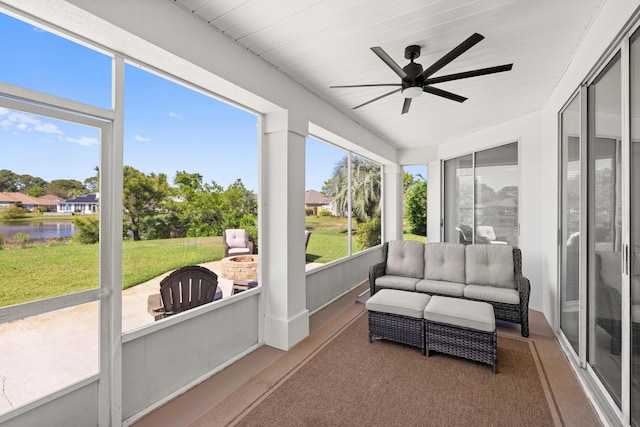 sunroom featuring a water view, a ceiling fan, and an outdoor living space with a fire pit