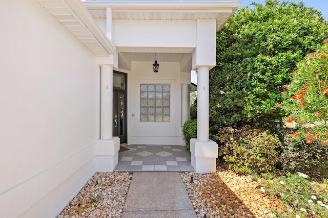 doorway to property featuring covered porch and stucco siding