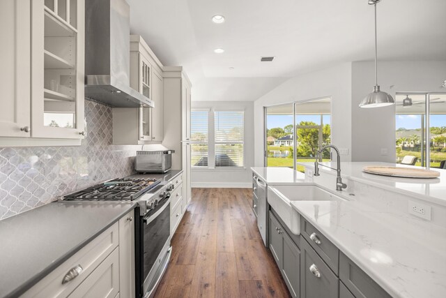 kitchen with wall chimney exhaust hood, tasteful backsplash, visible vents, a sink, and stainless steel appliances