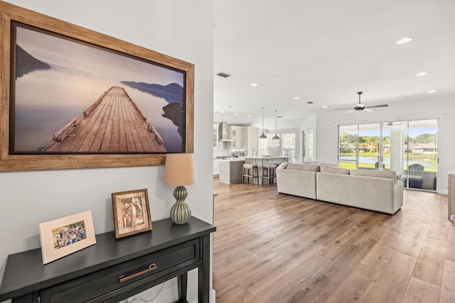 living area featuring visible vents, ceiling fan, light wood finished floors, and recessed lighting