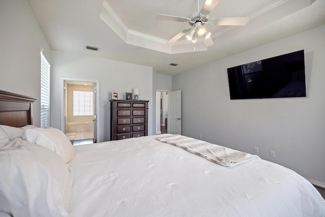 bedroom with ensuite bathroom, a textured ceiling, crown molding, visible vents, and a tray ceiling