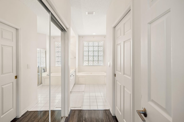 bathroom featuring a textured ceiling, a garden tub, wood finished floors, and visible vents