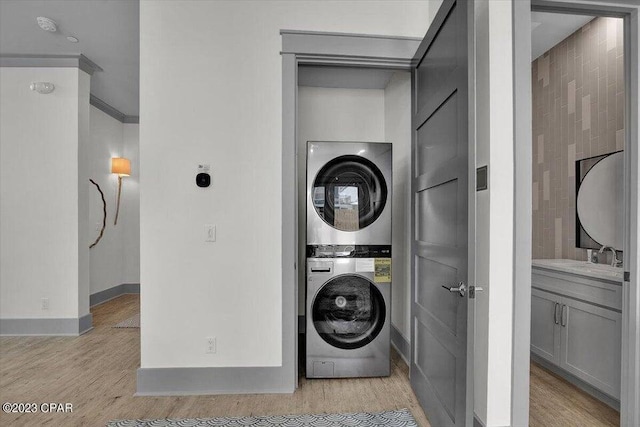8320 Surf Dr, Panama City Beach, FL 32408 - washroom with baseboards, laundry area, light wood-style flooring, a sink, and stacked washer and dryer