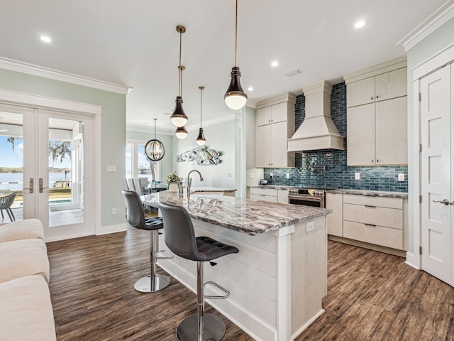 kitchen featuring crown molding, a sink, wall chimney exhaust hood, tasteful backsplash, and high end range