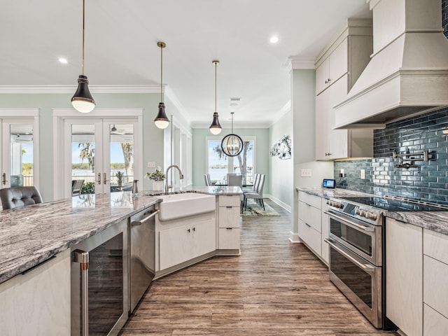 kitchen with ornamental molding, stainless steel appliances, a sink, beverage cooler, and custom exhaust hood