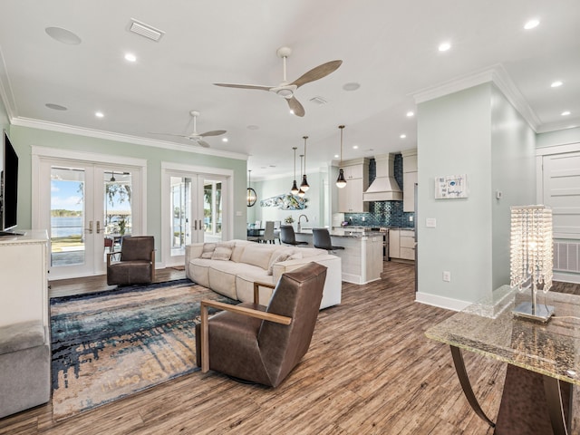 living room featuring french doors, wood finished floors, ornamental molding, and visible vents