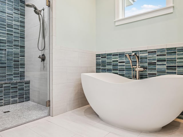bathroom with tile walls, a stall shower, tile patterned flooring, and a freestanding bath