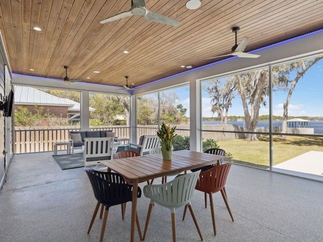 sunroom featuring outdoor dining area, a ceiling fan, an outdoor hangout area, and a water view