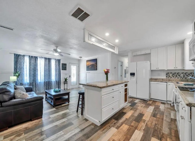 kitchen featuring open floor plan, white appliances, a center island, and visible vents
