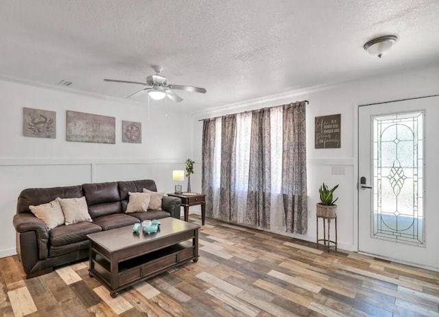 living room featuring a textured ceiling, crown molding, ceiling fan, and wood finished floors