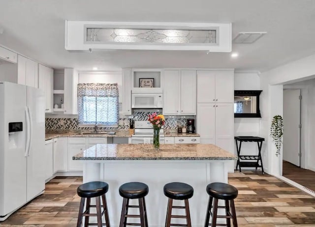 kitchen featuring white appliances, a breakfast bar area, backsplash, and a sink