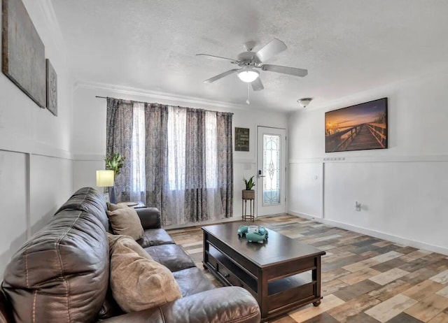living area featuring wainscoting, a textured ceiling, a ceiling fan, and wood finished floors