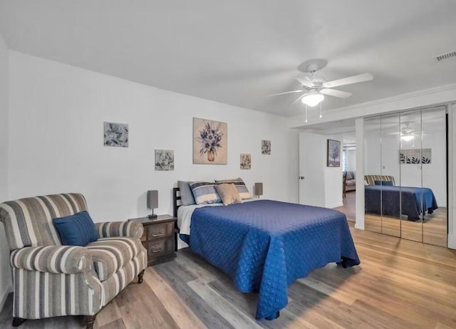 bedroom with visible vents, wood finished floors, and a ceiling fan