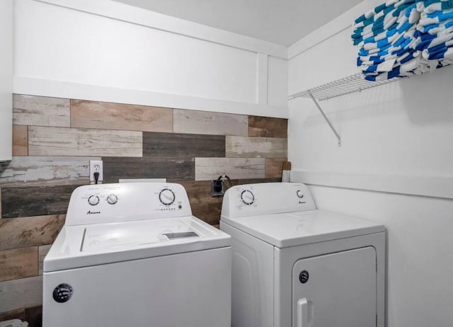 laundry area with laundry area, washing machine and dryer, and wood walls