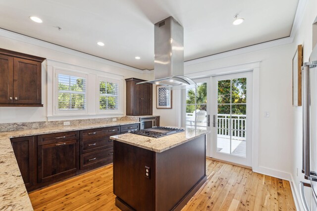 1848 E County Highway 30a Unit 4, Santa Rosa Beach, FL 32459 - kitchen with healthy amount of natural light, island exhaust hood, dark brown cabinets, light wood finished floors, and ornamental molding